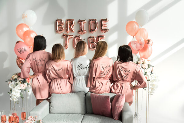 Bride,with,girlfriends,in,silk,robes,at,a,bachelorette,party.